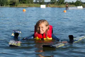 Süsel Seeparx - junges Mädchen mit Wakeboard im Wasser beim Schwimmen an Land
